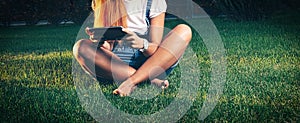 Studente in park e-learning on tablet PC sitting cross-legged on the grass photo