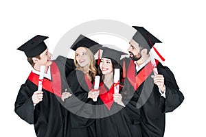 Students in academic caps standing embracing with diplomas