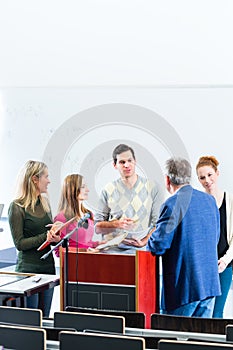 Students asking professor in college auditorium