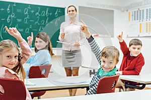 Students in class raising hands to answer a question
