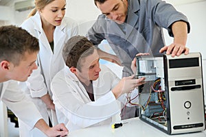 Students in a class with teacher repairing hardware