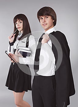 Students. Confident teenagers in school uniform portrait. Handsome boy and beautiful girl holding books posing at camera, isolate