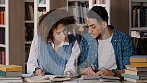 Students do homework in library teamwork working on joint project cute girl explaining task to male friend write notes