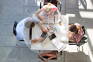 Students doing group projects while sitting on table at university library