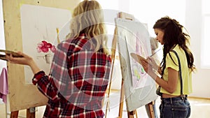 Students with easels painting at art school