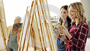 Students with easels painting at art school