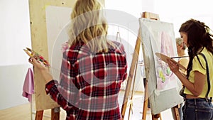 Students with easels painting at art school