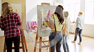 Students with easels painting at art school