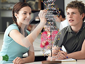 Students Examining DNA Model And Taking Notes