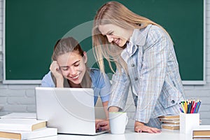 Students girls looking at laptop computer in classroom at school college. Two students doing homework together and