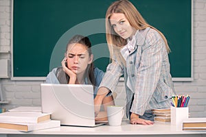 Students girls looking at laptop computer in classroom at school college or university. Two students doing homework