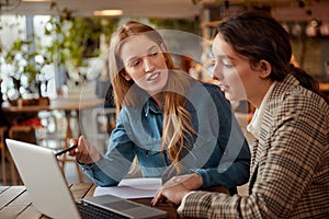 Students. Girls Studying With Laptop. Beautiful Young Women Having Lesson At Cafe.