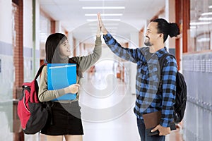 Students give high five in school corridor