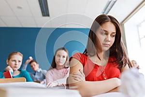 Students gossiping behind classmate back at school photo