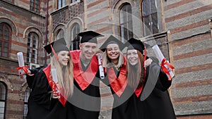 Students graduates hugging laughing having fun background of the university.