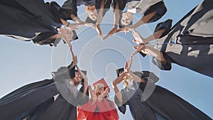 Students graduating from the college make a heart out of their hands.