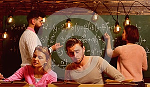 Students, group mates studying, while teacher asking girl near chalkboard. Exam concept. Bearded teacher, , professor