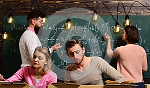 Students, group mates studying, while teacher asking girl near chalkboard. Exam concept. Bearded teacher, , professor