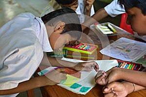 Students hands holding colored pencils painting on art drawing paper