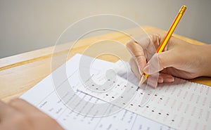 Students hands taking exams, writing examination room with holding pencil on optical form of standardized test with answers and e