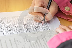 Students hands taking exams, writing examination room with holding pencil on optical form of standardized test with answers and