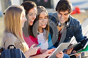 Students having fun with smartphones and tablets after class