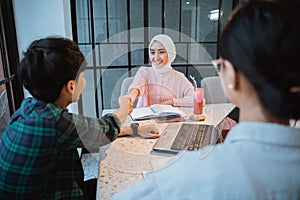 students in headscarves shake hands with male students getting acquainted