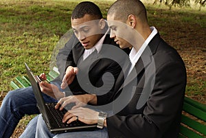 Due amici, navigando in internet sul suo computer portatile e il cellulare all'aperto.
