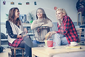 Students learning in a cafe. Three friends having conversation.