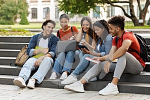 Students Leisure. Group of multiethnic college friends resting in campus outdoors