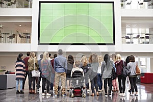 Students looking up at a big screen in university atrium