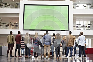 Students looking up at a big screen in university building