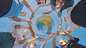 Students make a circle around the globe of the world. The concept of world peace.