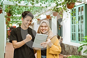 Students male and hijab girl happy when looking to the screen of the tablet photo