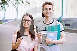 Students near university holding credit cards and smiling to camera