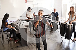 Students At Performing Arts School Playing In Band At Rehearsal With Teacher