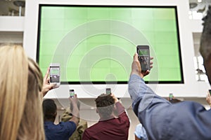 Students photograph screen with phones, back view, close up