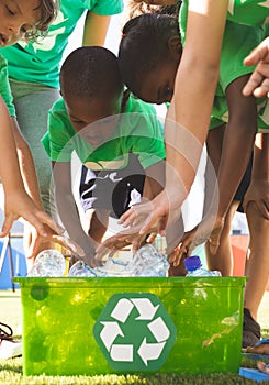 Students putting plastic bottles on dustbin in schoolyard