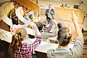Students raising hands with teacher in lecture hall