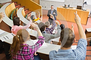 Students raising hands with teacher in the lecture hall photo