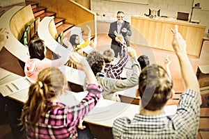 Students raising hands with teacher in lecture hall photo