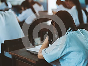 Students reading exam answer sheets exercises in classroom of school with headache.and stress