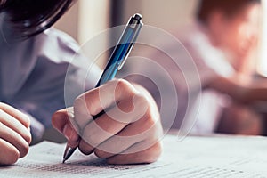 Students reading and writing answer doing exam in classroom with stress