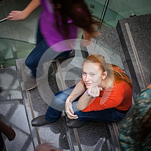 Students rushing up and down a busy stairway -  young female student looking upwards
