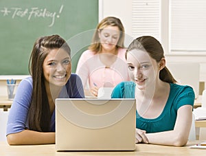 Students sharing laptop in classroom