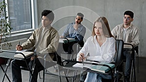 Students sit at desk in classroom attentive listen lecture at seminar write notes prepare for exam business audience at