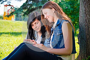 Students sitting in park with tablet pc
