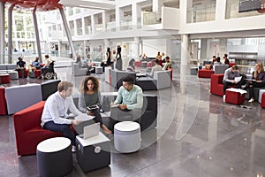 Students sitting in university atrium, three in foreground photo