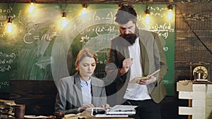 Students study with professor in retro school classroom. Teacher standing in front of a chalkboard in a class.