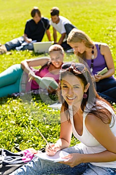 Students studying sitting on grass in park